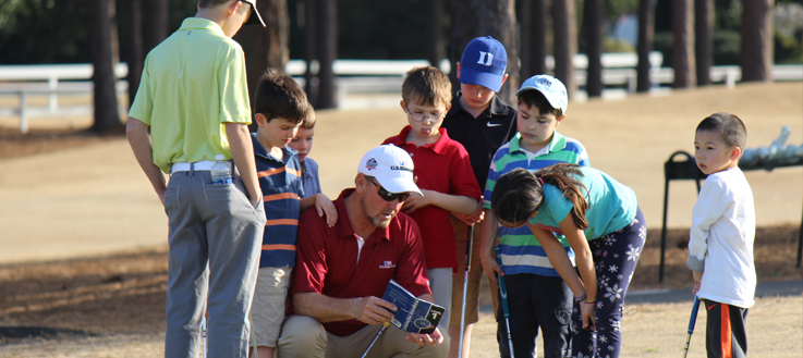 golf instructor talking with young golf students