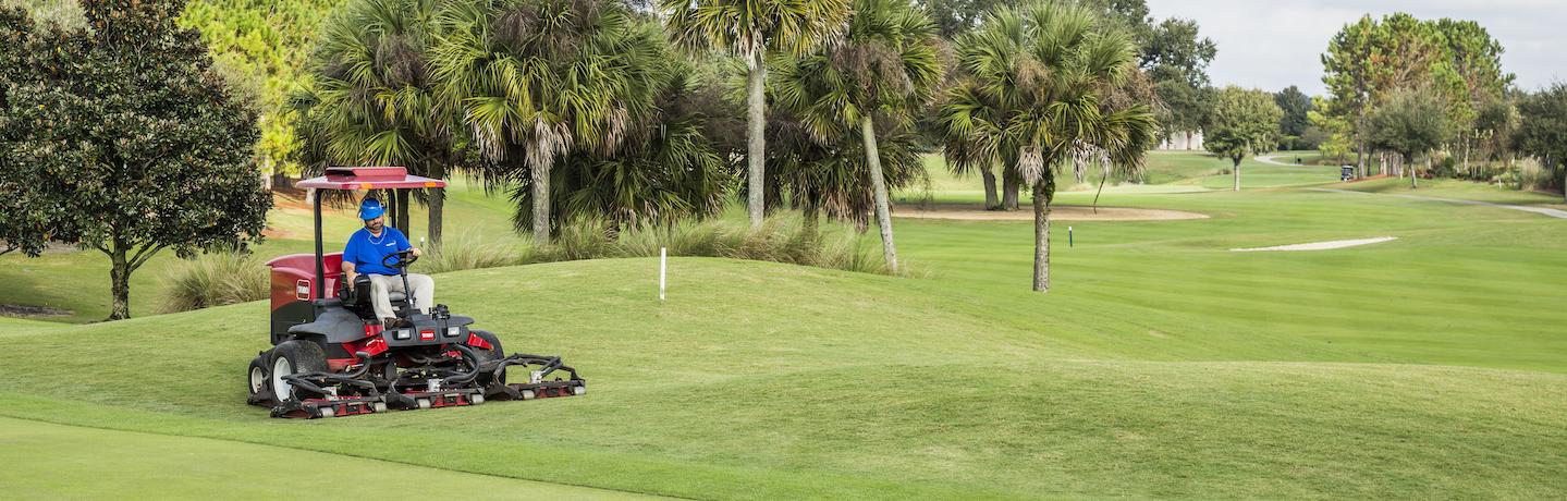 Crew member operating mower on golf course